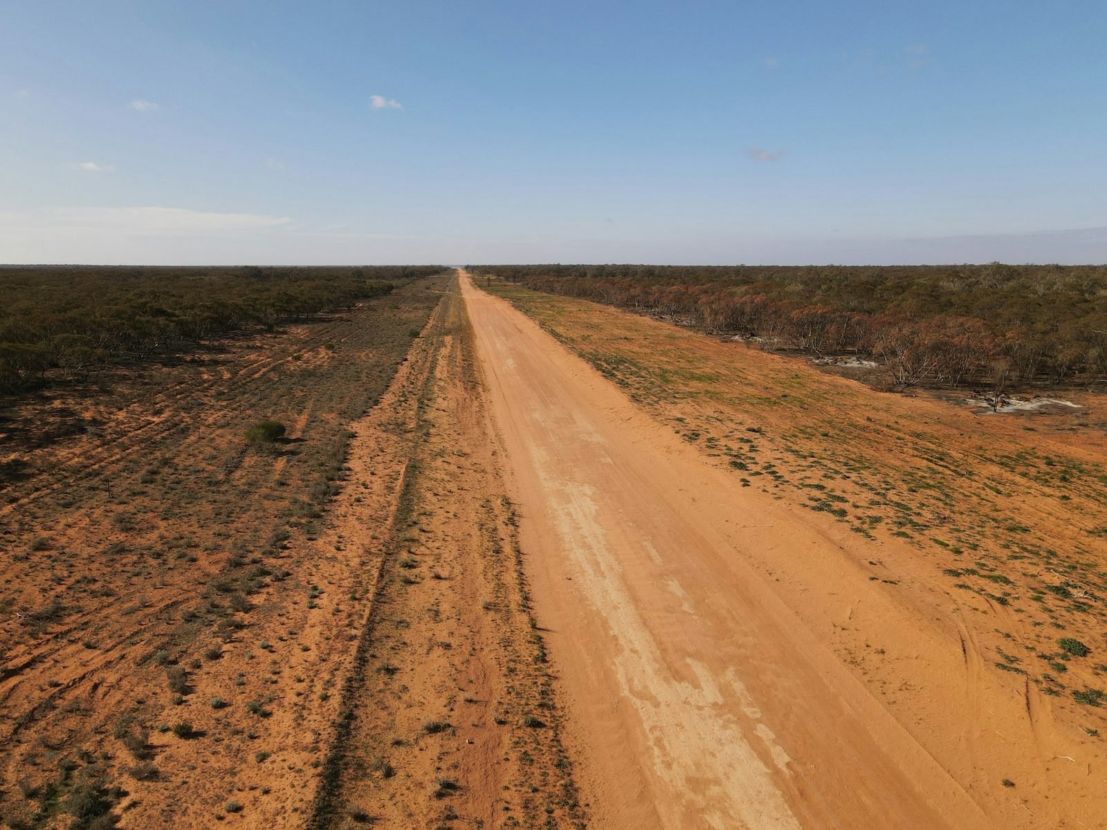Aerial view down a red-murram bush airstrip cut through Uganda scrubland
