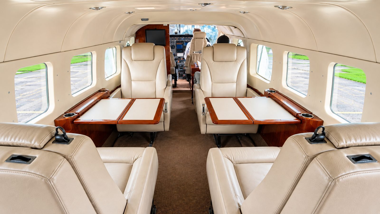 The cream-leather executive cabin of an Asante Aviation Grand Caravan, with club seating and burl-wood tables